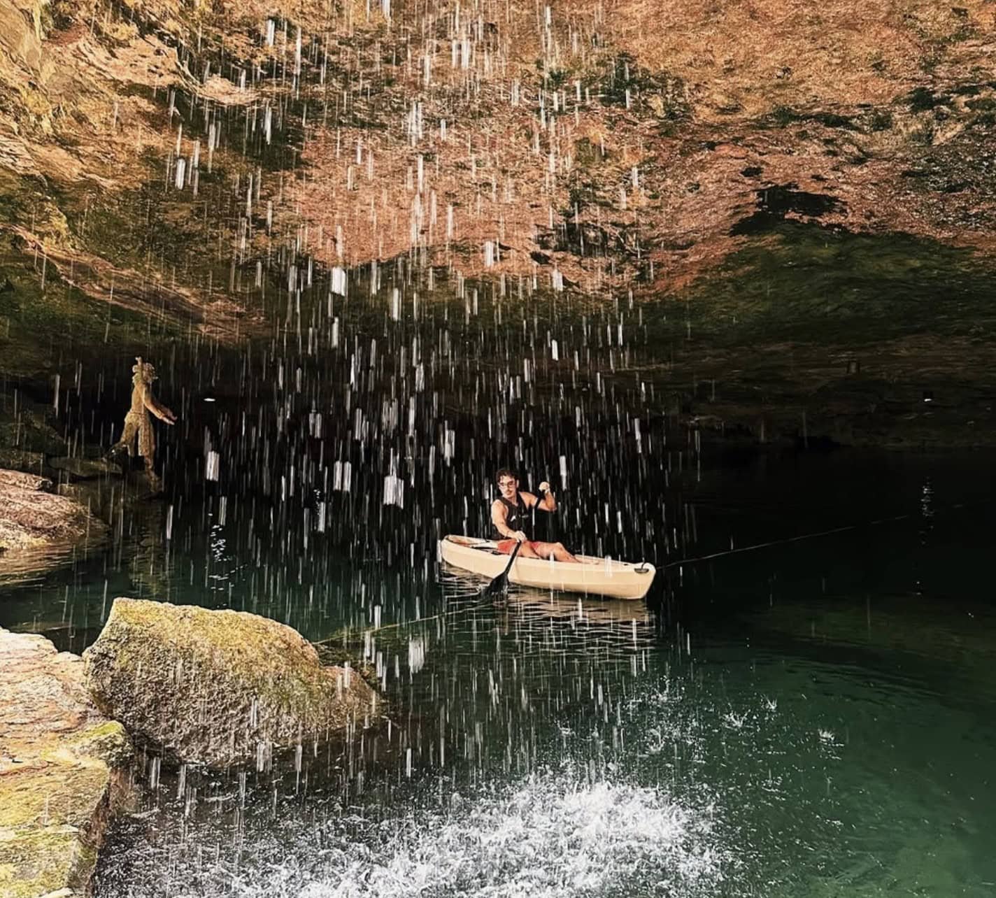 Cenote Cristalino: Full Guide (is it worth it in 2026?) 5 Man kayaking under a waterfall at cenote Cristalino