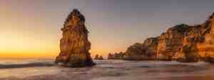 A stunning coastal landscape at sunset with rock formations and calm ocean waves at Praia Dona Ana