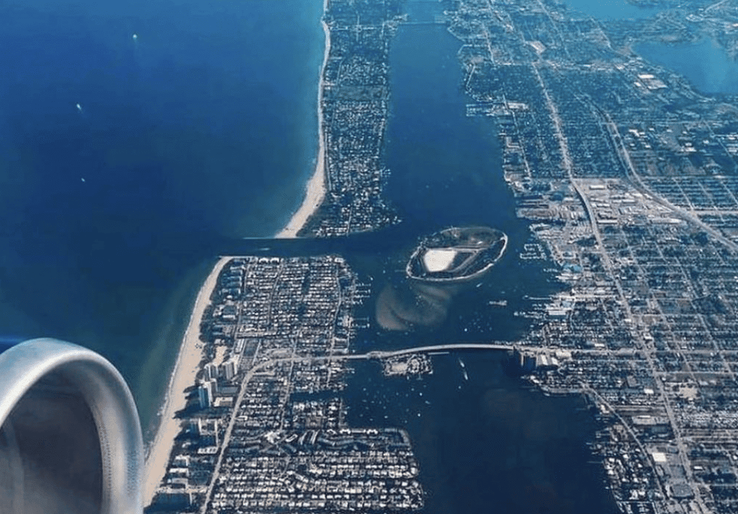 Navigating Lake Worth Inlet FL, in 2026 1 Aerial view from an airplane showing a coastal city with a long stretch of beach along the ocean, intersected by a wide inlet and bridge.