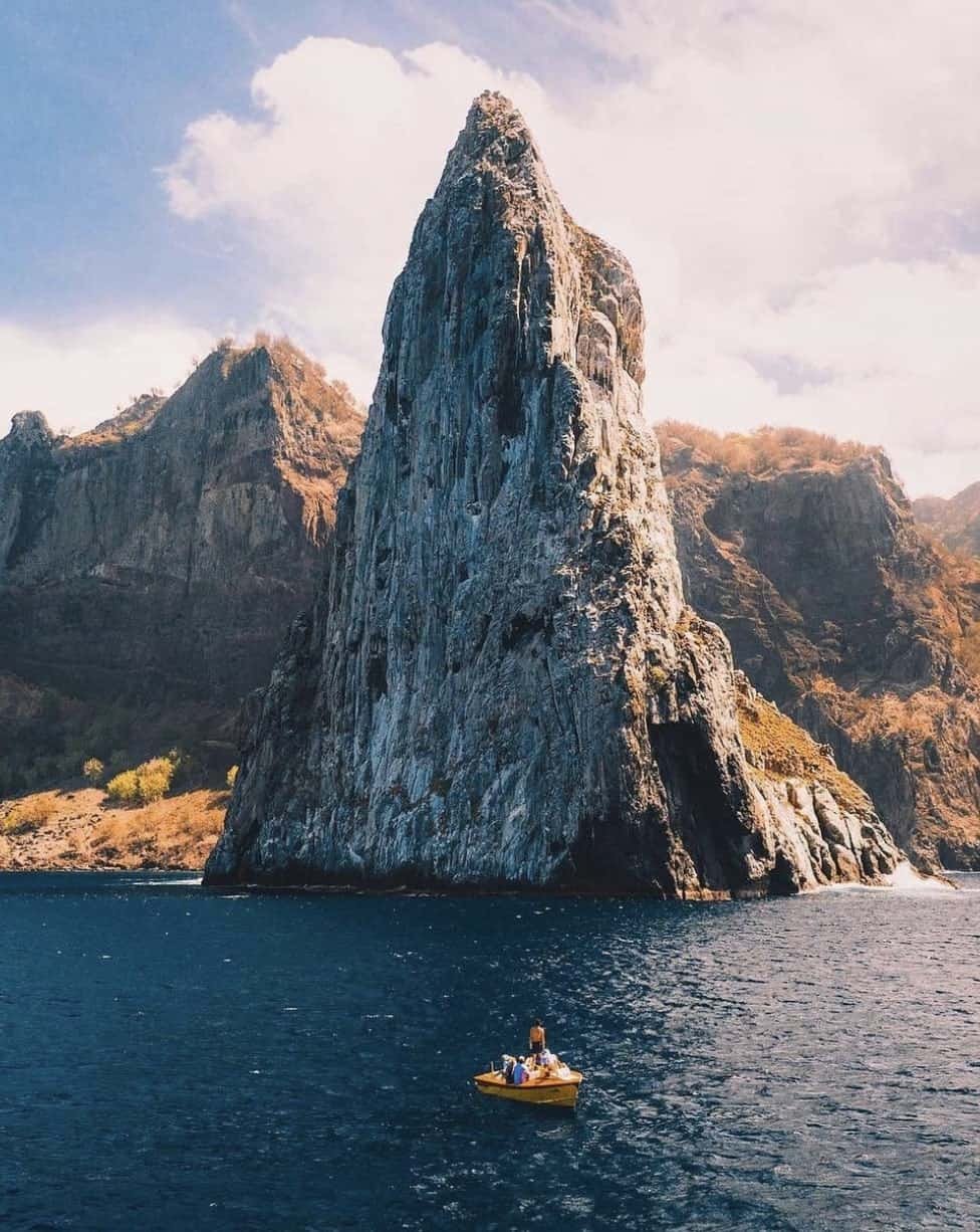 Ua Pou Marquesas Islands: A Full Guide For First-Timers 10 a boat in the water with a tall rock formation in the background from Ua Pou island in French Polynesia