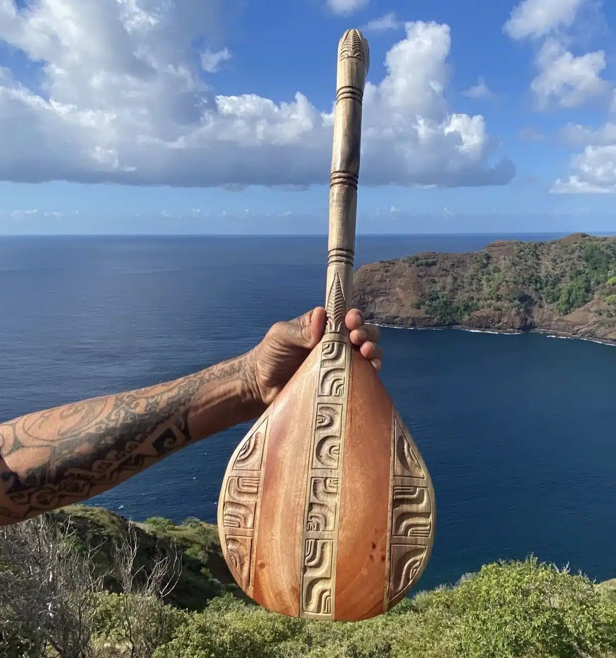 A person holding a wooden object with a body of water in the background.