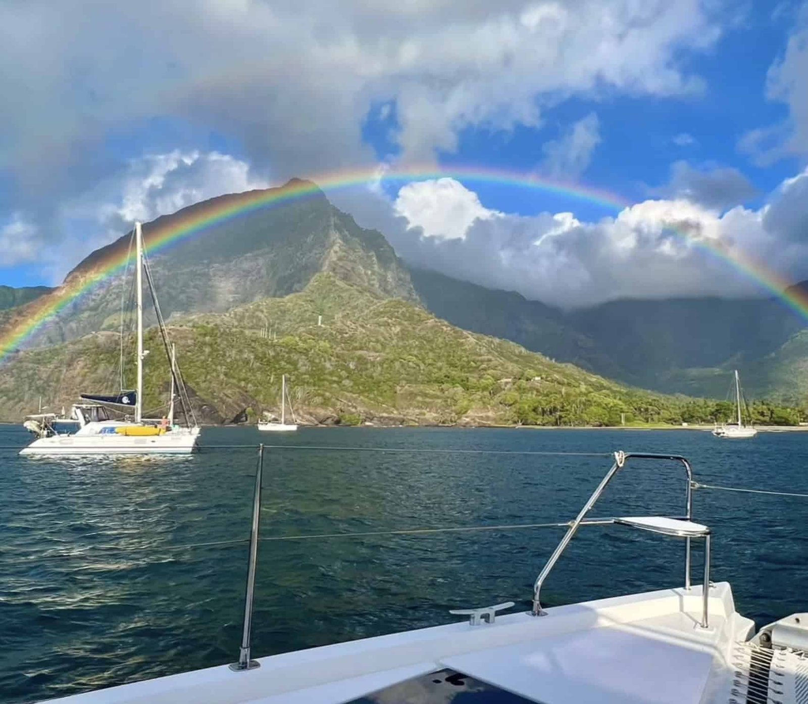 Why Visit Hiva Oa Island (TOP Things to do + Itinerary)! 2 a rainbow over a mountain and boats on water at Hiva Oa