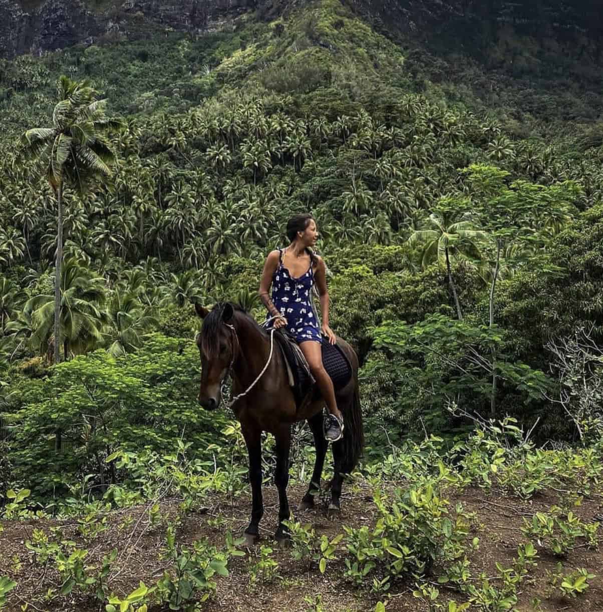 A woman riding a horse in a forest at Hiva Oa island.