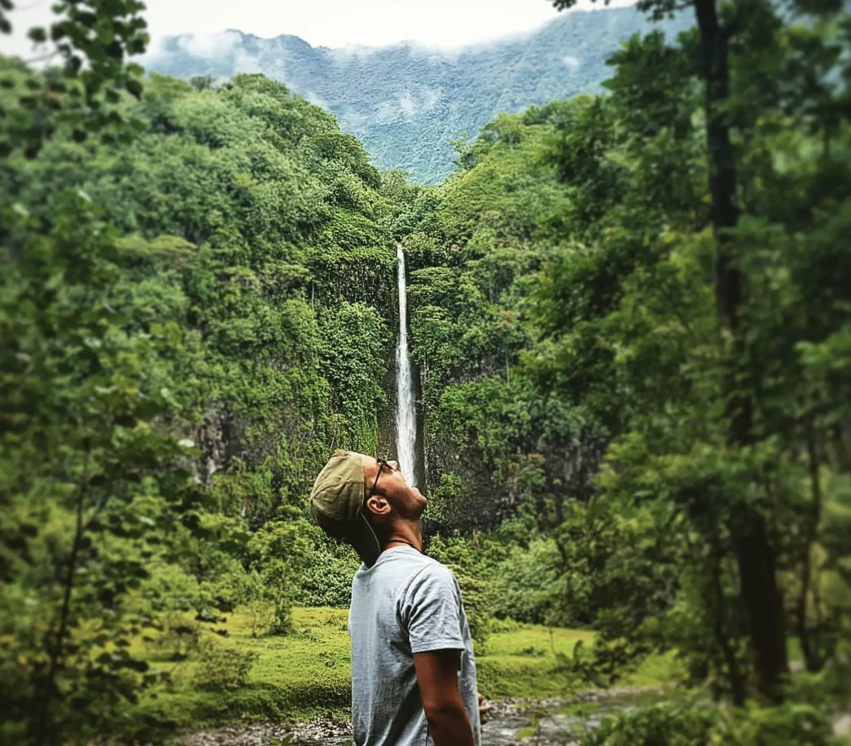 Guy standing in front of one of the Papenoo Valley Waterfalls.