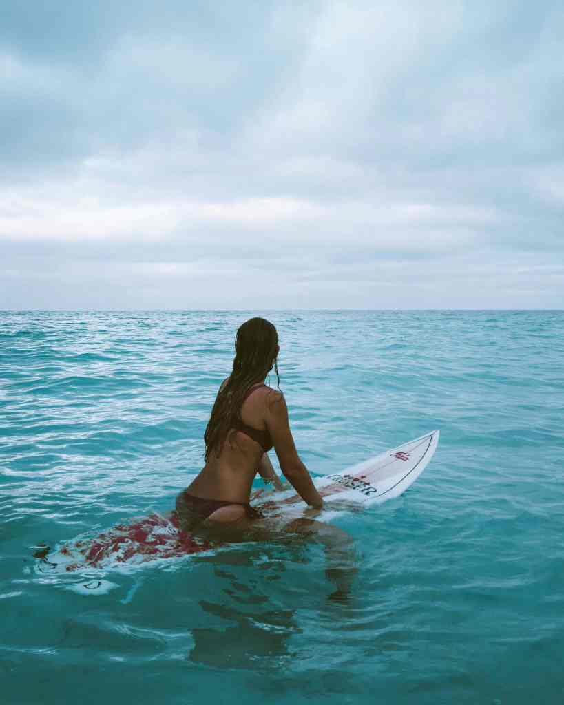 Woman sitting on surfboard