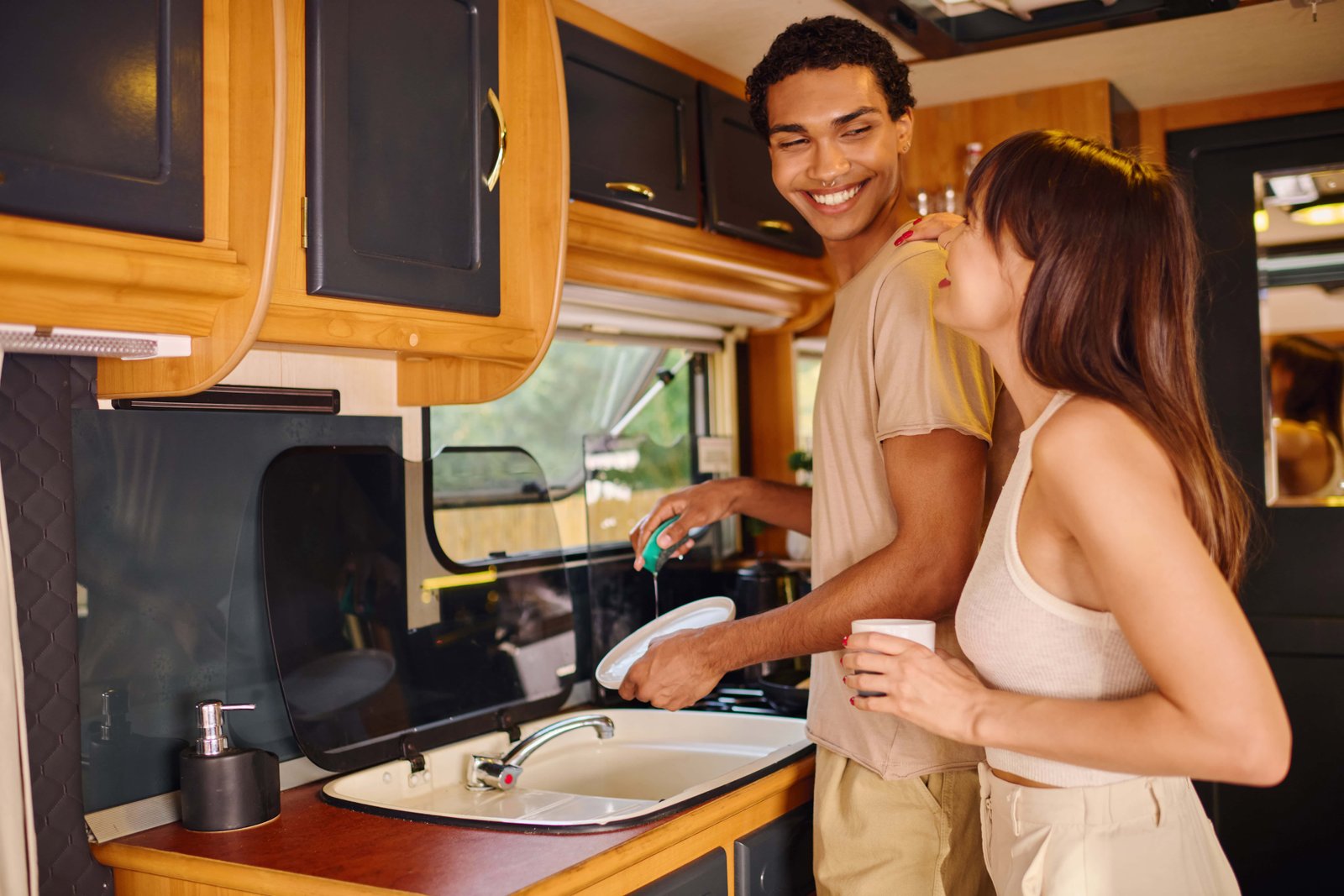 How to Plan an RV Road Trip Across the United States? 2 A man and woman, of different ethnicities, stand in a kitchen next to a sink.
