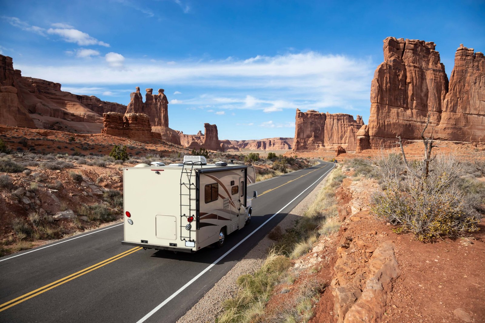 How to Plan an RV Road Trip Across the United States? 1 Camper riding on a Scenic road in the red rock canyons during a vibrant sunny day. Taken in Arches National Park, located near Moab, Utah, United States.