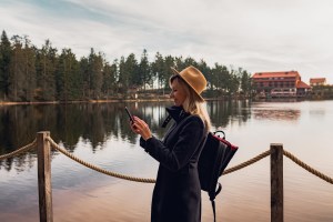 stylish girl in hat with-backpack is on her phone