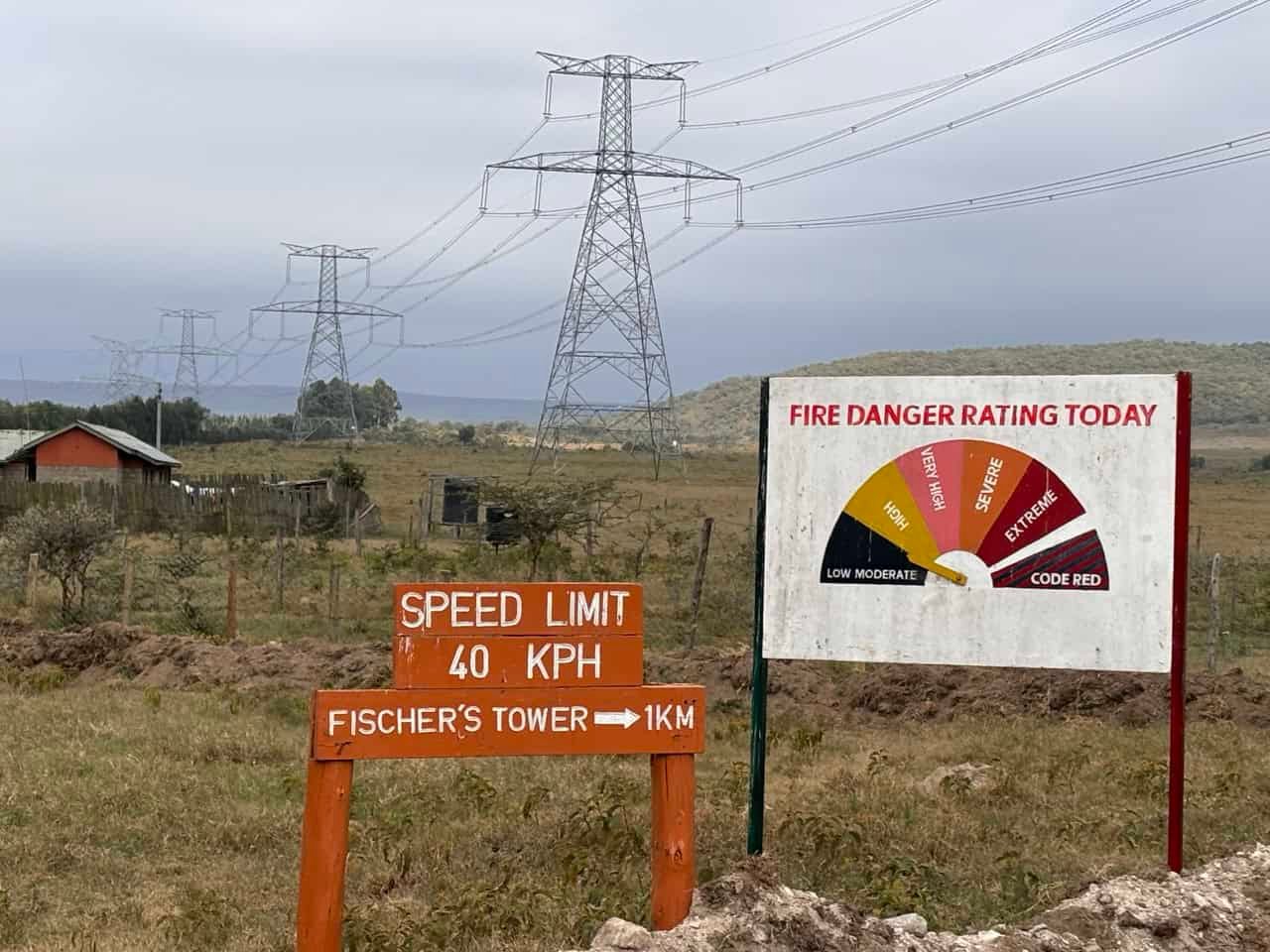 Naivasha in Kenya Travel Guide (With Itinerary and Tips) for 2026! 24 High voltage power lines over rural landscape with fire danger rating sign and speed limit sign, illustrating outdoor safety and infrastructure, with emphasis on fire hazard awareness and electrical power transmission.
