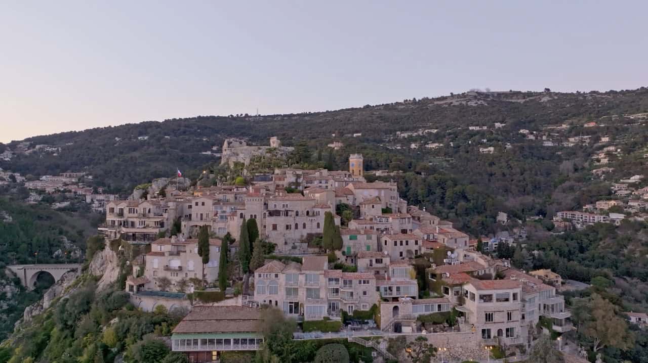 Luxurious hillside Èze village overlooking the ocean with lush greenery, historic architecture, and scenic coastal views in the Lost Between Oceans setting.