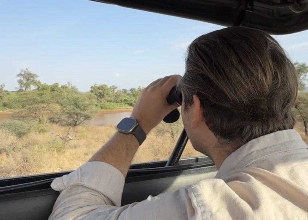 Alexander from Lost Between Oceans looking through binoculars in Kenya