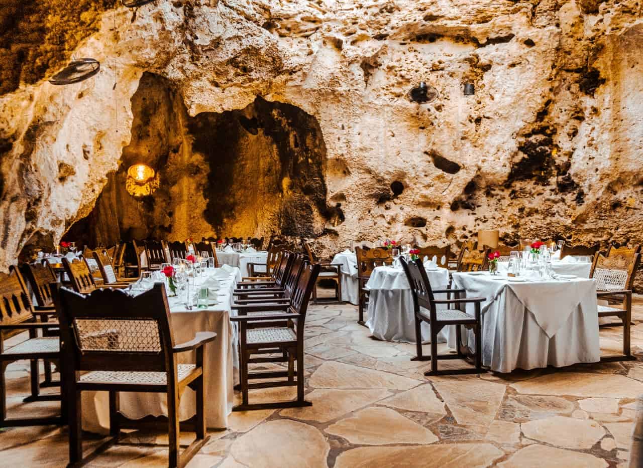 Ali Barbour Cave inside tables and chairs with the natural rock formation on the background